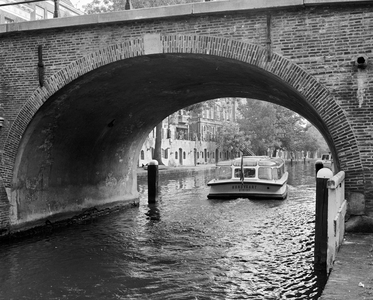 857955 Gezicht op de Oudegracht te Utrecht, van onder de Geertebrug, met een rondvaartboot.